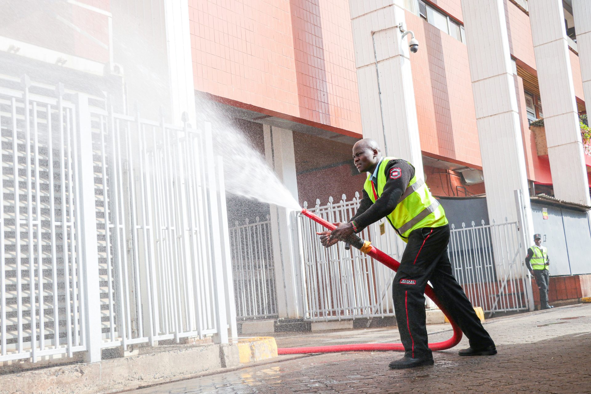 Man in safety vest sprays water from hose