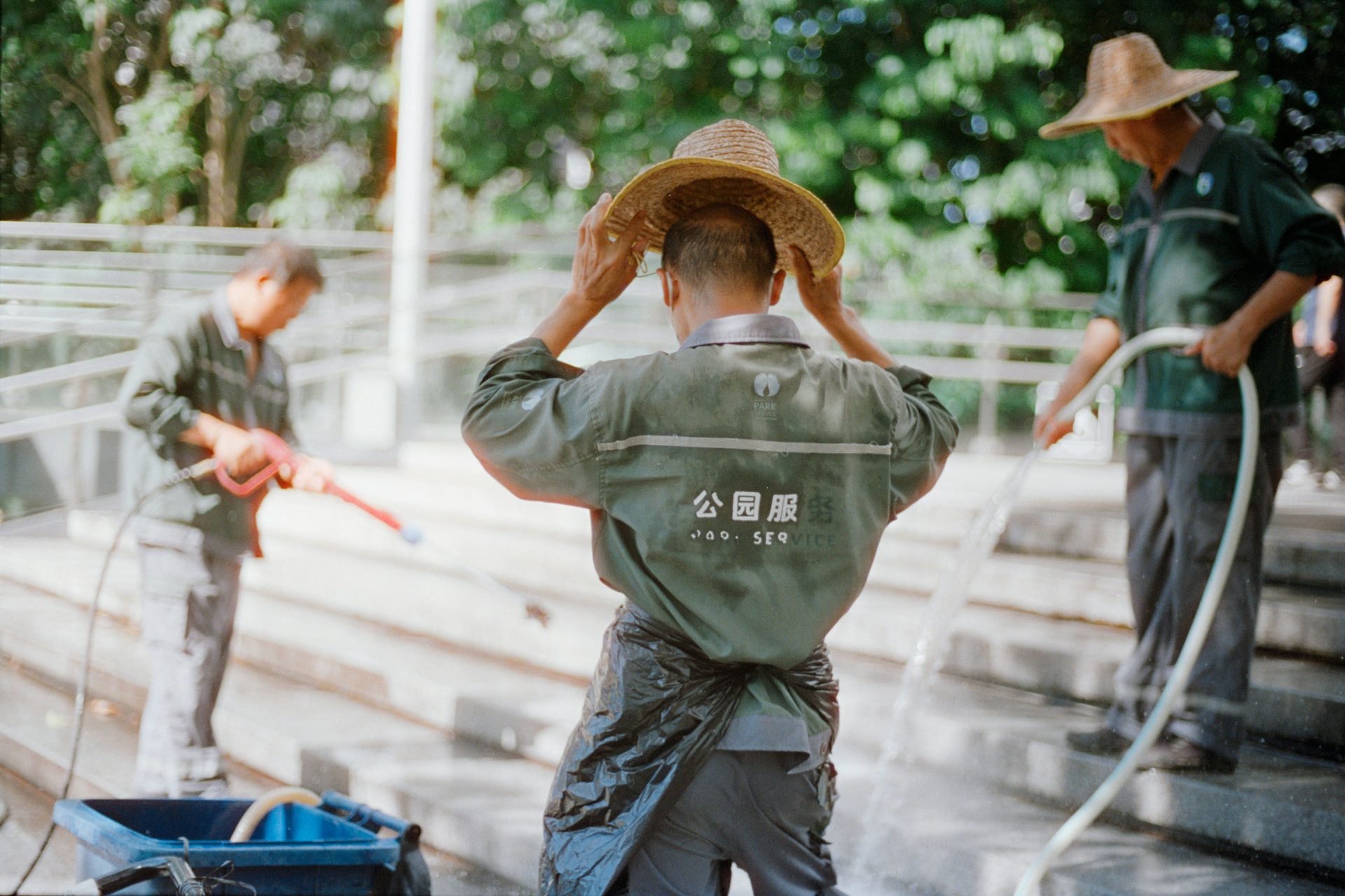 Three workers in hats watering plants outdoors
