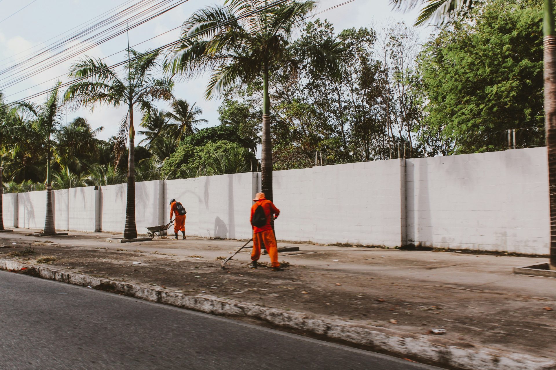 man in orange robe standing near palm trees during daytime